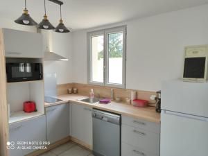 a kitchen with white cabinets and a white refrigerator at le carpe diem in Onzain