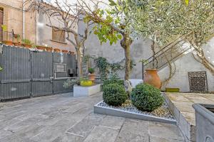 a courtyard with trees and bushes and a fence at Maison Capucine in Mèze