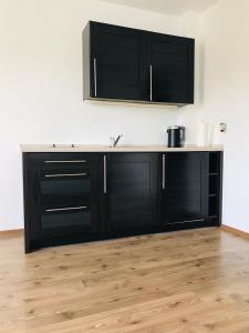 a kitchen with black cabinets and a wooden floor at Apartament Marina Mazury in Węgorzewo