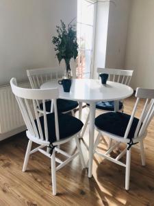 a white dining room table with two chairs and a plant at Apartament Marina Mazury in Węgorzewo