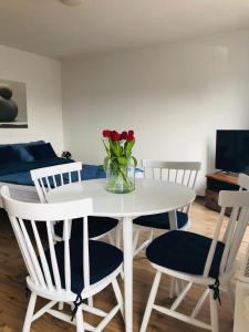 a white dining room table with a vase of flowers on it at Apartament Marina Mazury in Węgorzewo