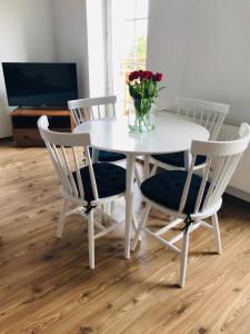 a white table with four chairs and a vase of flowers at Apartament Marina Mazury in Węgorzewo