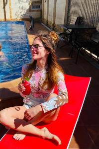 Eine Frau, die auf einer roten Matte neben einem Pool sitzt. in der Unterkunft Отель Колизей in Dagomys