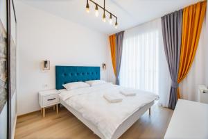 a bedroom with a large white bed and a blue headboard at Panorama Views - Spacious Central Apartment in Oradea