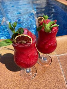 Dois cocktails em taças de vinho ao lado de uma piscina em Отель Колизей em Dagomys