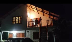 duas pessoas de pé na varanda de uma casa à noite em Cabaña El Trebol em San Agustín