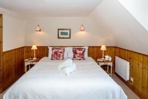 a bedroom with a large white bed with two lamps at Hotel Eilean Iarmain in Isleornsay