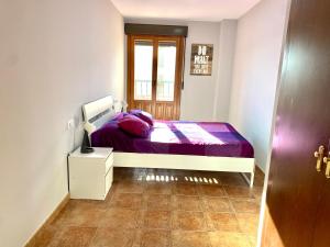 Un dormitorio con una cama con sábanas moradas y una ventana. en Costa Esuri Golf y Playa V, en Ayamonte 7 fotos más