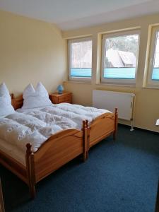 a bedroom with a large wooden bed with white sheets at Ferienwohnung 6, Waldesruh Dierhagen in Dierhagen