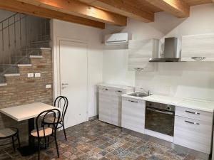 a kitchen with white cabinets and a table and chairs at Delta House in Taglio di Po