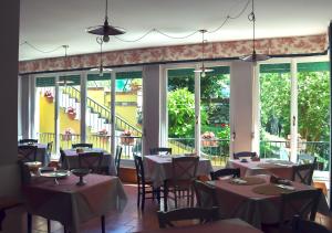 - une salle à manger avec des tables, des chaises et des fenêtres dans l'établissement Pineta del Borgo, à Cavi di Lavagna