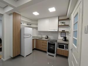eine Küche mit einem weißen Kühlschrank und Holzschränken in der Unterkunft Apartamento Aluri in Porto Alegre