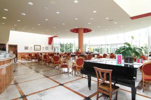 a restaurant with tables and chairs and a piano at Hotel Begoña Park in Gijón