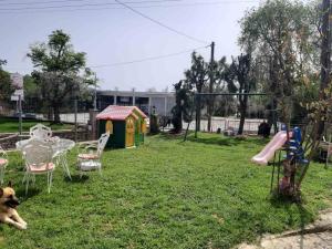 a dog laying in a yard with a table and a playground at Palio Villa in Paleo Tsifliki