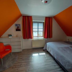 - une chambre avec des rideaux orange, un lit et une chaise dans l'établissement Ferienwohnung Urlaub mit Pferd, Hof Müggenburg, à Stüdenitz