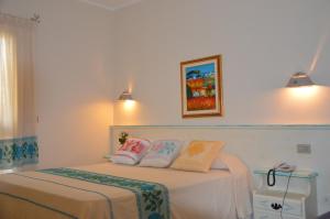 a bedroom with a bed with two pillows on it at Hotel La Palma in San Teodoro