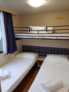 two beds in a dorm room with three bunk beds at FKK Ulika - Naturist Mobile Homes Eden in Poreč