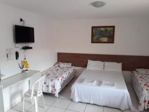 a bedroom with two beds and a desk and a tv at Pousada CERTRI in Triunfo
