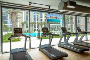 a gym with cardio equipment and a large window at A Luxury Aprt 2 bedrooms Balcony with wonderful view Mall access hi speed WIFI Beach access & much more for Family Only in Rayyā