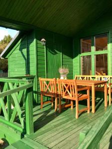 a green house with a wooden table and chairs on a deck at Domek Green Dźwirzyno in Dźwirzyno