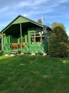ein grünes Haus mit einer Veranda auf einem Hof in der Unterkunft Domek Green Dźwirzyno in Dźwirzyno