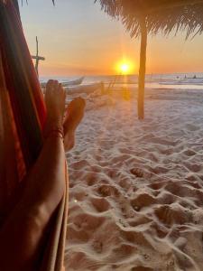 a person sitting in a hammock on the beach at sunset at Urantia Beach Hostel & Surf Camp in San Onofre