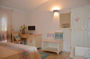a bedroom with two beds and a desk and a tv at Hotel La Palma in San Teodoro