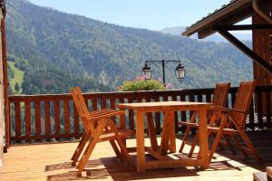 une table et des chaises en bois sur une terrasse avec vue dans l'établissement Chalet La Fedora - Appartements de charme, à Vaujany