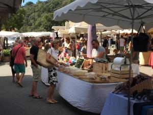 a group of people standing next to a market with a boat at CHARME RAMATUELLE in Ramatuelle