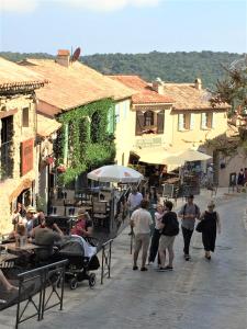 a group of people walking down a street with buildings at CHARME RAMATUELLE in Ramatuelle