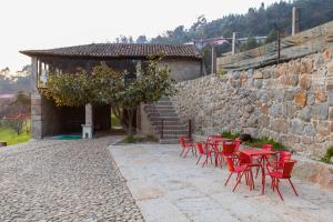 un grupo de mesas y sillas rojas junto a una pared de piedra en Quinta dos Campos - Chalé, en Braga