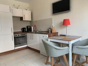 a small kitchen with a table and chairs and a television at Ostwind - ferienwohnungen & meer in Steffenshagen