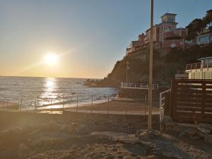 a sunset on a beach with a building on a hill at Caletta Beach in Castiglioncello