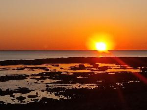 a sunset over the ocean with the sun setting at Caletta Beach in Castiglioncello