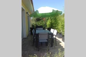 einen Tisch, Stühle und einen Regenschirm auf einer Terrasse in der Unterkunft Suite spacieuse avec accès piscine in Ghisonaccia