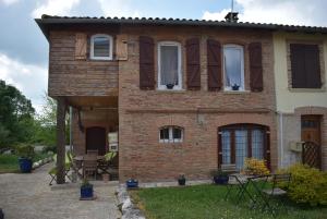 uma casa de tijolos com janelas e um pátio em Maison de charme dans le Gers em Noilhan