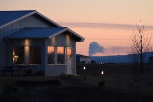 una pequeña casa con una puesta de sol en el fondo en Lambastadir Guesthouse en Selfoss