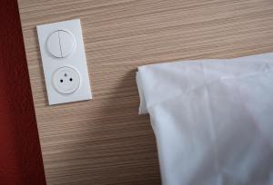 a close up of a bed with a light switch at Premiere Classe Beaune in Beaune