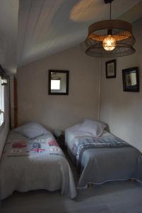 a bedroom with two beds and a chandelier at Maison de charme dans le Gers in Noilhan