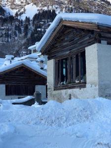 una casa en la nieve con nieve en el suelo en Chalet Ca d'Martin en Vicosoprano