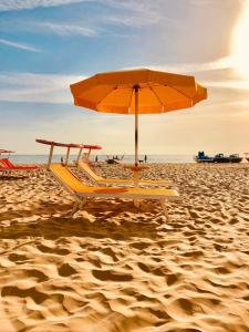 una spiaggia con ombrellone e sedie sulla sabbia di Hotel Villa Lieta a Rimini