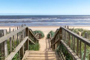 a wooden staircase leading to a beach with the ocean at Pine Drive Golden Sands Mablethorpe in Mablethorpe