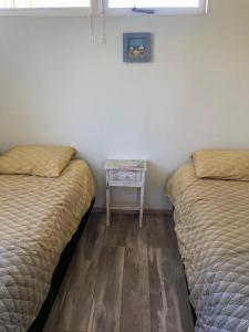 - 2 lits dans une chambre avec une table de chevet dans l'établissement Vakantiehuisje in Ouddorp dichtbij het strand, à Ouddorp