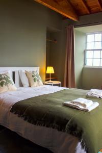 a bedroom with a large bed with a green blanket at The House in São Roque do Pico