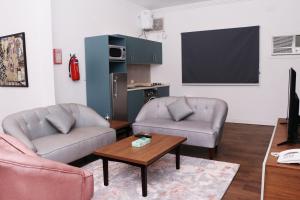 a living room with two chairs and a tv at مندرين للشقق المخدومة in Taif