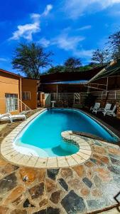 a large swimming pool with a stone pathway around it at YoIeli Guest House in Windhoek