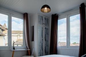 a bedroom with windows and a bed and a lamp at Hôtel & Gastronomie - La Table de l'Europe in Villeréal