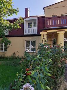 a house with a balcony and a garden with flowers at Pensjonat Stary Busko Zdrój in Busko-Zdrój