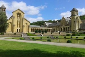 un grande edificio con un laghetto di fronte di Le repaire des belettes Vallée de Rabais a Virton