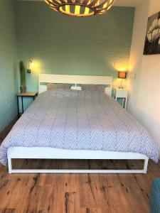 - une chambre avec un grand lit et un couvre-lit blanc dans l'établissement Casa Nuestra, à Egmond aan Zee